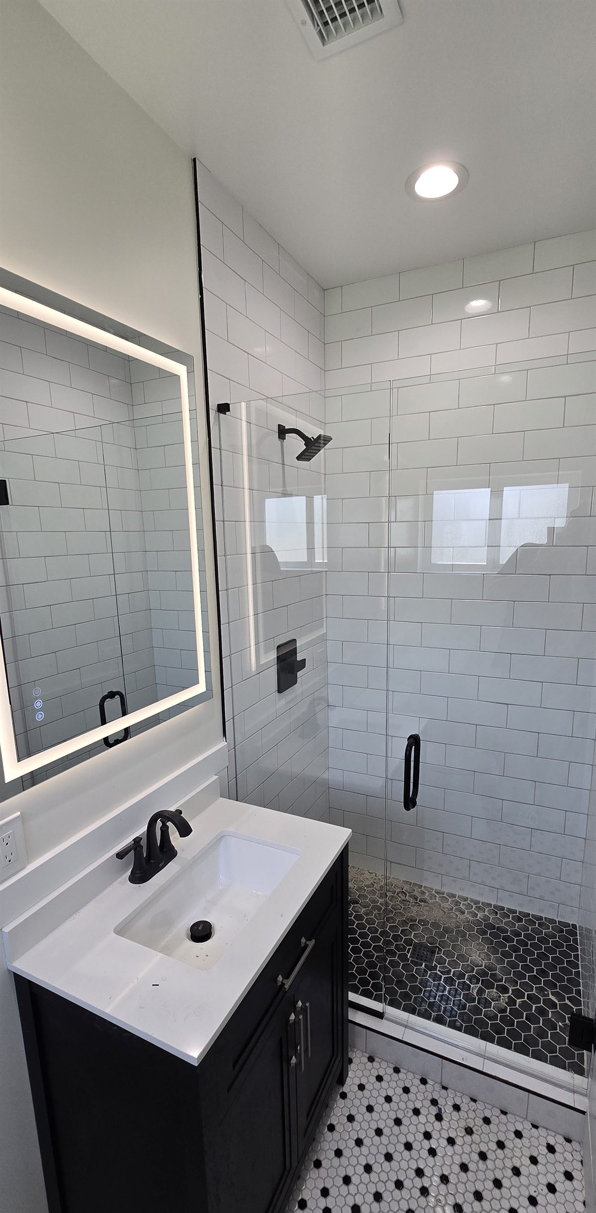 Finished secondary bathroom with subway tile and black hex floor