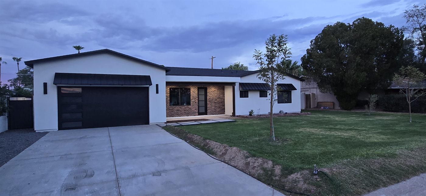The same home after SOKO's addition and remodel, with new stucco, brick, and modern finishes