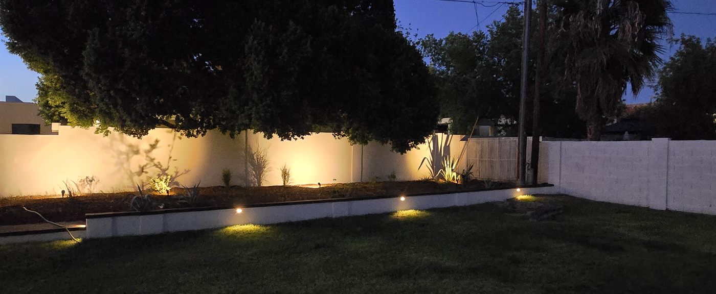 Finished backyard with new landscaping and lighting at dusk