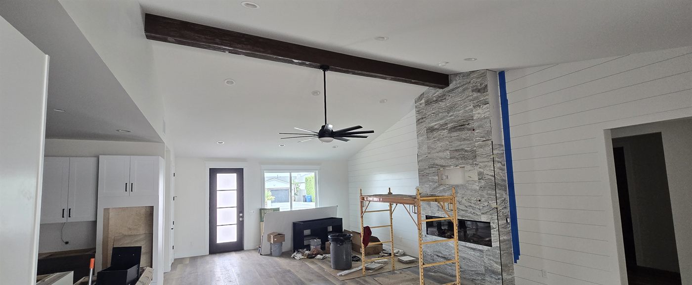 Living area with vaulted ceiling, wood beam, and floor-to-ceiling tile fireplace