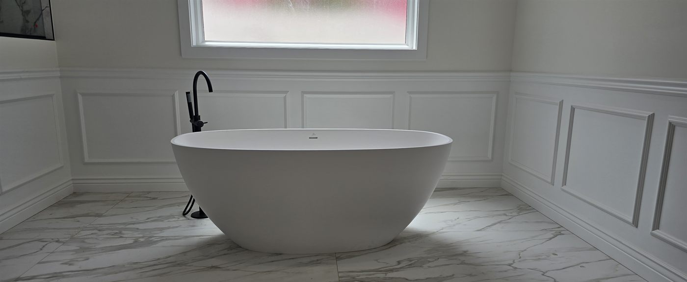 Primary bathroom with freestanding tub, wainscoting, and marble-look tile